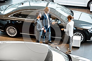 Business couple with salesperson in the car showroom