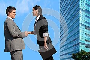 Business couple shaking hands over deal outdoors.