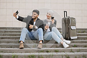 Business couple sitting on the stairs outside airport.