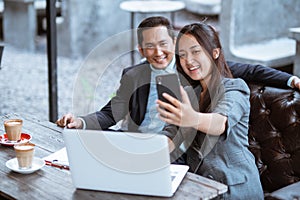 business couple taking a photo of herself using smartphone