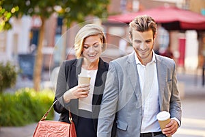 Business Couple Walking Through Park With Takeaway Coffee