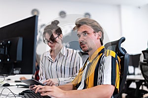 Business couple working together on project using tablet and desktop computer at modern open plan startup office