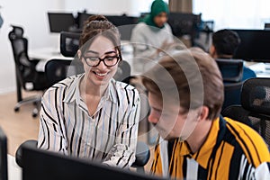 Business couple working together on project using tablet and desktop computer at modern open plan startup office