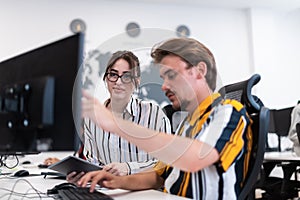 Business couple working together on project using tablet and desktop computer at modern open plan startup office