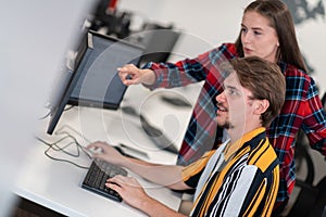 Business couple working together on project using tablet and desktop computer at modern open plan startup office