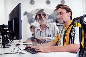 Business couple working together on project using tablet and desktop computer at modern open plan startup office