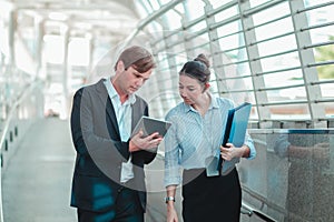 Business couples are discussing business issues while walking on the skywalk Both are busy working all day. And still holding the