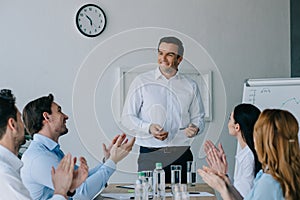 business coworkers applauding to smiling mentor while having business training