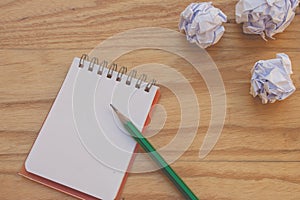 Business Creative and Idea Concept : Used green pencil put on notebook with white crumpled paper ball put on wooden table.