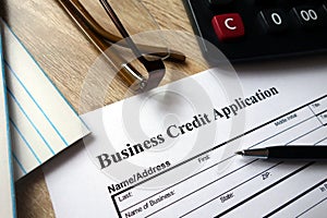 Business credit application form with pen, calculator and glasses