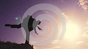 business crisis teamwork concept. man businessman silhouette at sunset standing on the edge of the abyss peak top