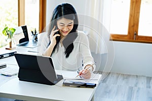 business dealings, an Asian company secretary is on the phone with customers comes to contact with using pen to write