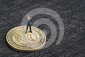 Business decision, investment risk, decline or say no concept, miniature businessman thinking and standing on gold coin face with