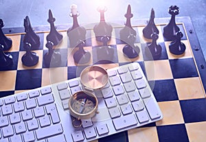 Business development strategy and direction concept with chess, compass and computer keyboard.