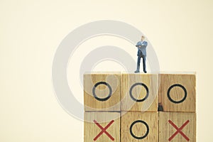 Business direction and planning concept. Businessman miniature standing and thinking on o x board games. Tic Tac Toe. Business photo