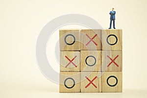 Business direction and planning concept. Businessman miniature standing and thinking on o x board games. Tic Tac Toe. photo