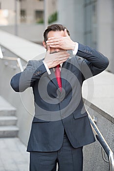 Business director keeping his palms in front of eyes and mouth