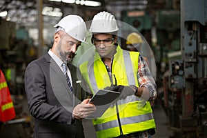 Business director and Mechanic engineer checking and discussing at factory shop floor