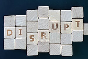 Business disruption, evolve or game changer concept, straggle cube wooden blocks with some combine the word DISRUPT on dark black photo