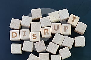 Business disruption, evolve or game changer concept, straggle cube wooden blocks with some combine the word DISRUPT on dark black photo