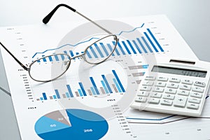 Business document, glasses, and calculator on gray reflection ba