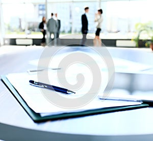 Business document in touchpad lying on the desk, office workers interacting in the background photo