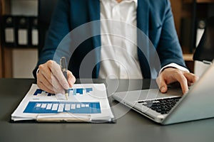 business documents on office desk with laptop and smart phone and graph business diagram and man working in morning light