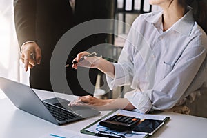 Business documents on office table with tablet and laptop computer and chart and two colleagues discussing data in office