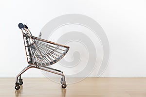 Business and E-Commerce Concept. CLose up of mini modern shopping cart / trolley on wooden table with copy space