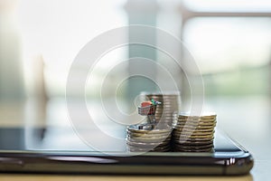 Business E-Commerce and Money Concept. Close up of shopping cart or trolley miniature figure on top of stack of coins on top on