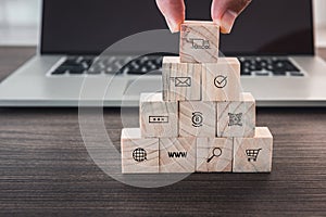 Business E-Commerce and Shopping Media Icons concept, Closeup finger man is pick up wooden cube from stack in front of computer