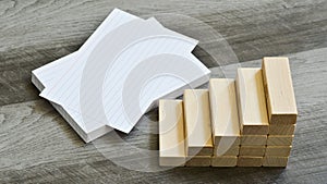 Business / Education Challenge Concept - Blank Index Cards With Stairway Upwards Of Building Blocks Over Dark Wooden Background
