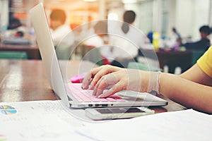 Business, education, people and technology concept - close up of female hands typing on keyboard of laptop computer with Blurred