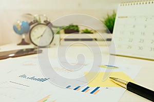 Business equipment include pen, graph paper, calendar placed on