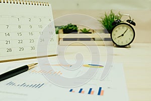 Business equipment include pen, graph paper, calendar placed on