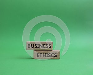 Business ethics symbol. Concept word Business ethics on wooden blocks. Beautiful green background. Business and Business ethics