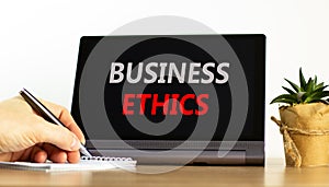 Business ethics symbol. Concept words Business ethics on beautiful black tablet. Beautiful white background. Businessman hand.