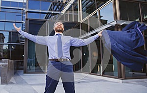 Business excitement. Business man keeping arms raised and expressing positivity outdoors. Businessman jumping for joy
