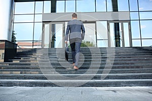 Business executive with briefcase going up the stairs.