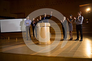 Business executive giving a speech while colleagues applauding