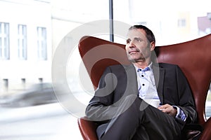 Business executive in red chair enjoying coffee.