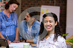 Business executive smiling and colleagues discussing in background