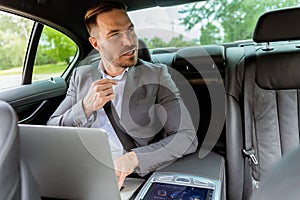 Business executive working on laptop in car during morning commute