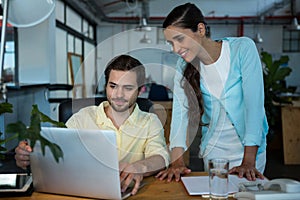 Business executives discussing over laptop