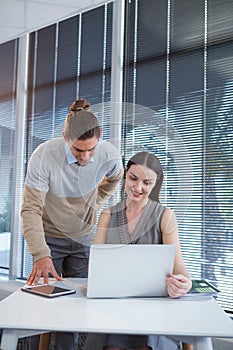 Business executives discussing over laptop at desk