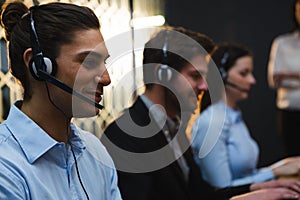 Business executives with headsets using computers at desk