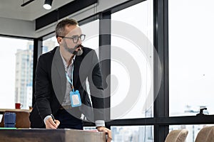 Business executives man look outside and thinking on create a new project and holding a pen and note some ideas in the notebook.