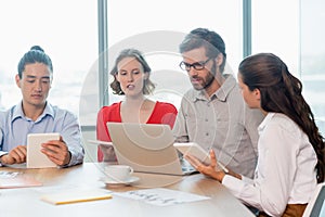 Business executives using laptop and digital tablet in conference room