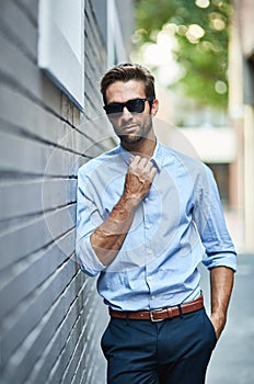Business fashion, confidence and portrait of man with glasses, professional clothes and leaning on city wall. Designer