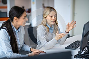 Business female colleagues are sitting at computer discussing report and devising new ways for business development